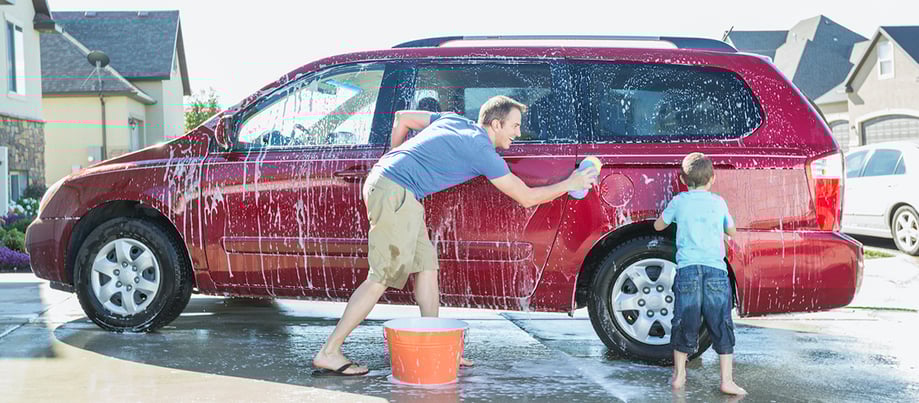 Man washing van with child